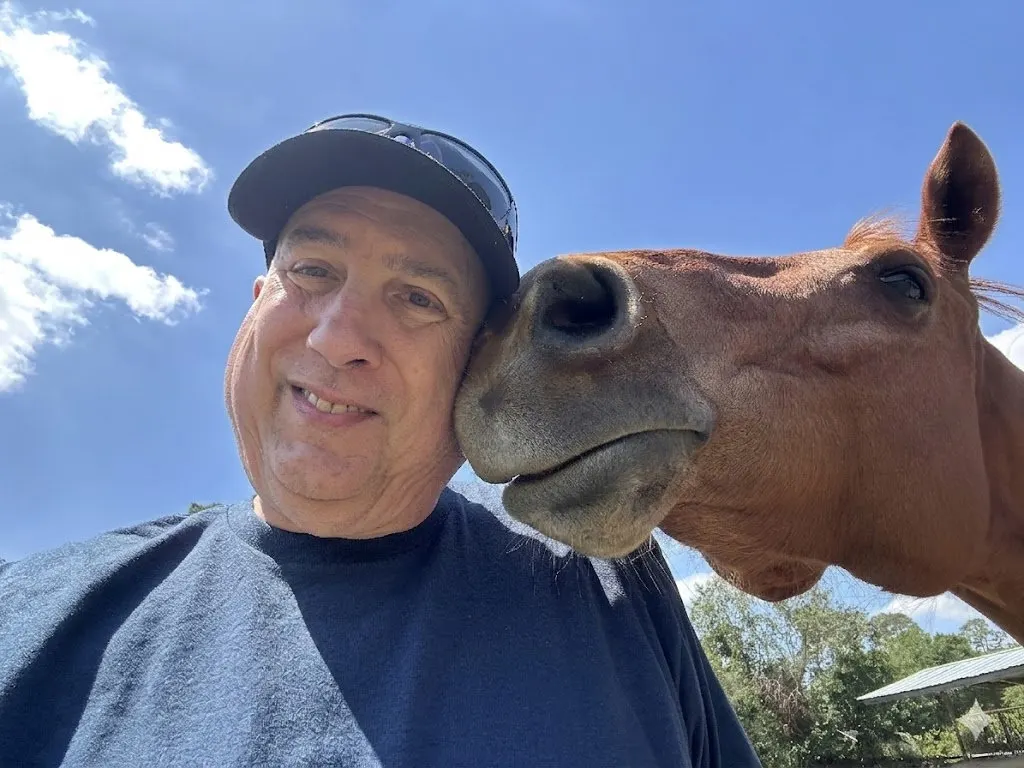 A visitor taking a selfie with a horse